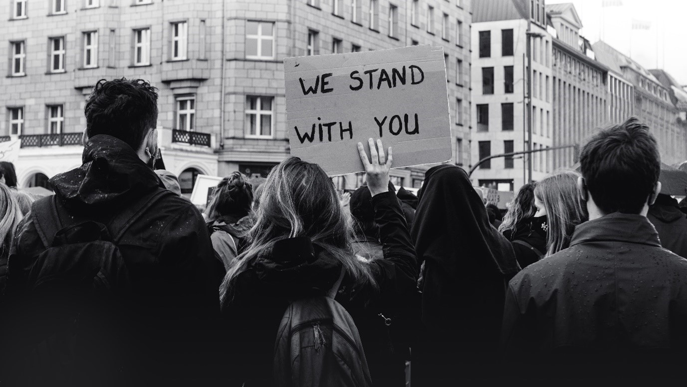 A group of people standing with a banner saying 'We Stand with you